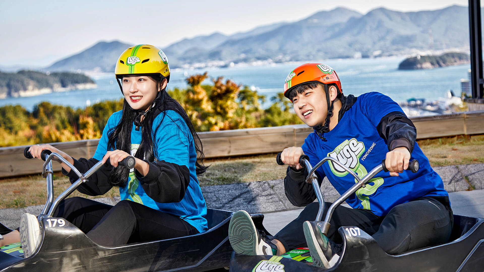 A man and woman race down the tracks at Skyline Luge Tongyeong.