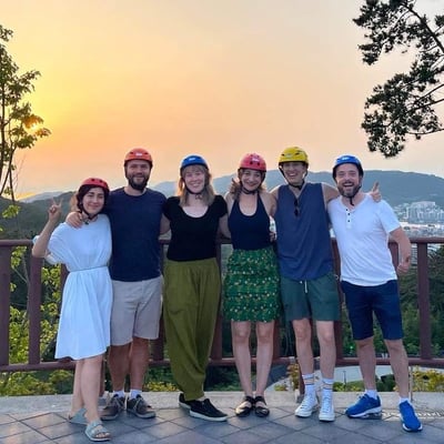 A group of friends pose for a photo at sunset with their Luge helmets on.
