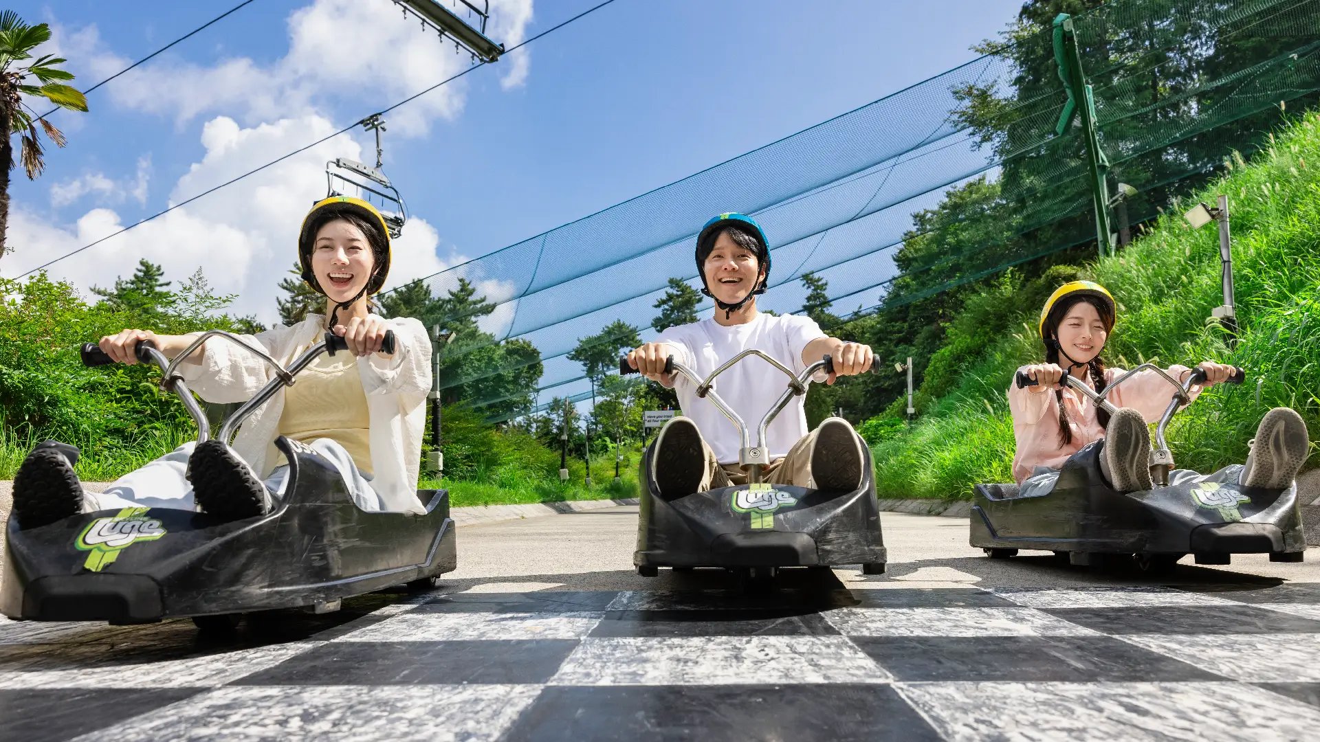 Riders crossing the finish line on the Skyline Luge Tongyeong track.