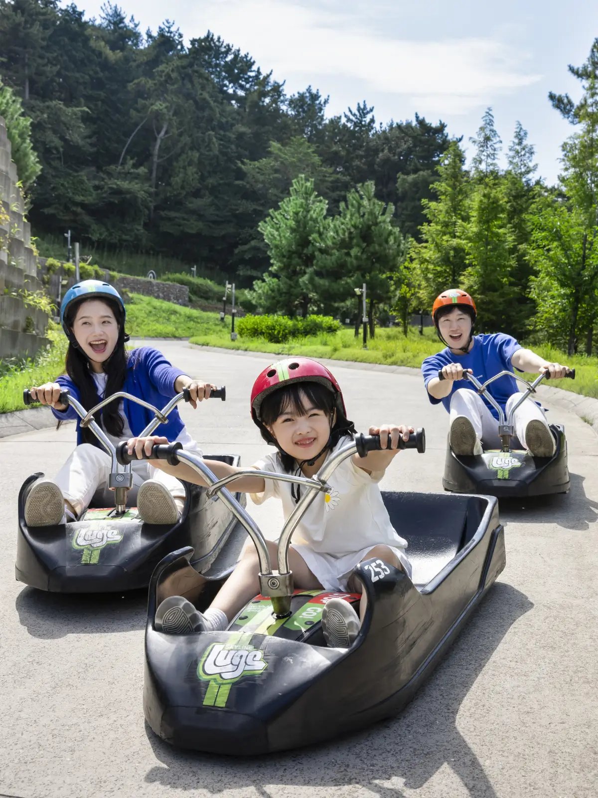 Experience the thrill of Skyline Luge Tongyeong as riders cruise down the track surrounded by scenic forest views.