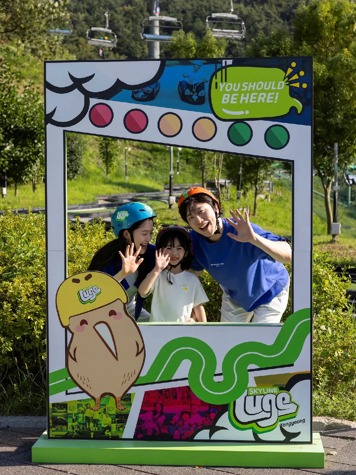 Guests posing at the Skyline Luge Tongyeong photo spot with themed signage.