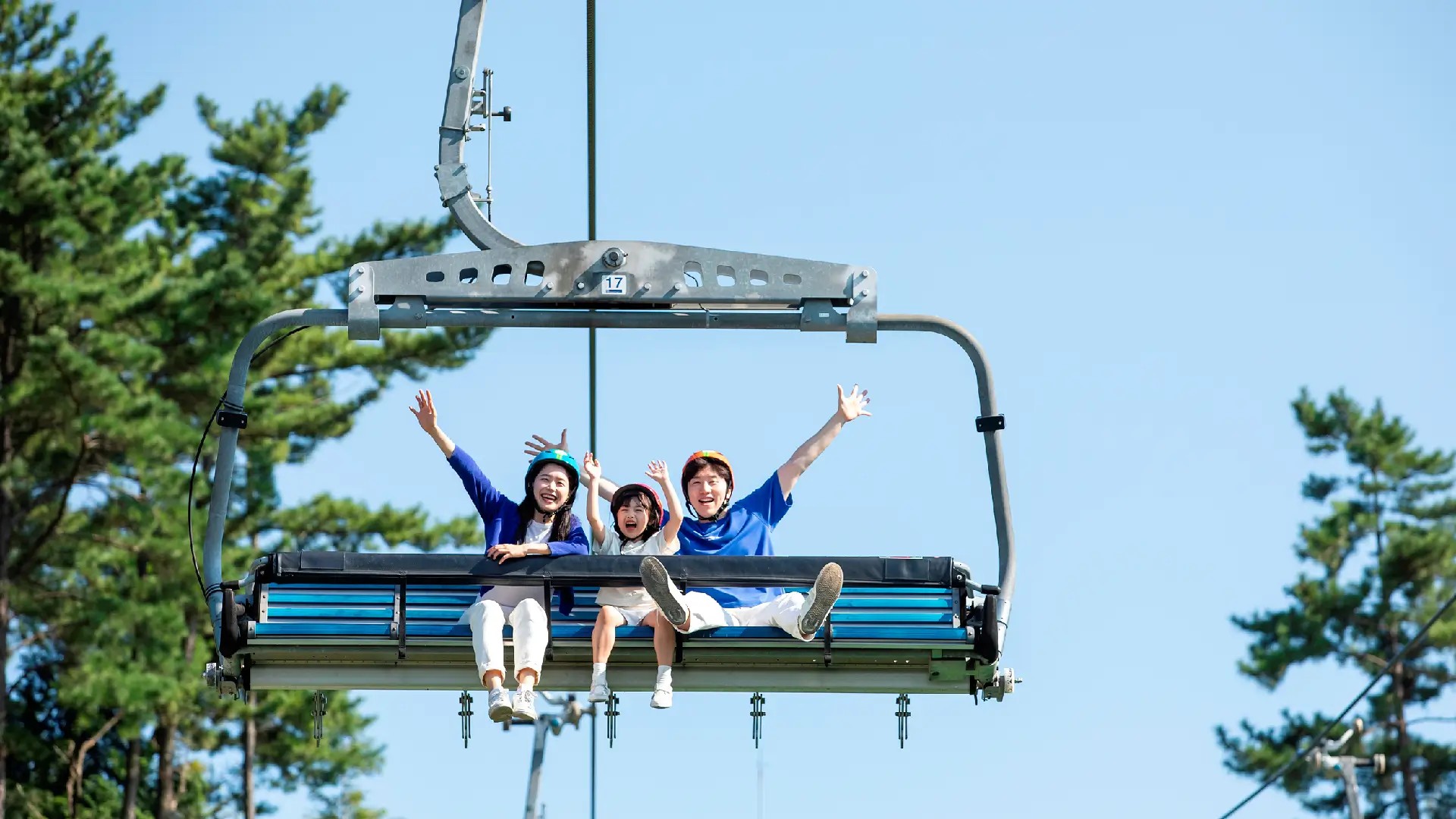 Group riding the Skyride at Skyline Luge Tongyeong with arms raised.