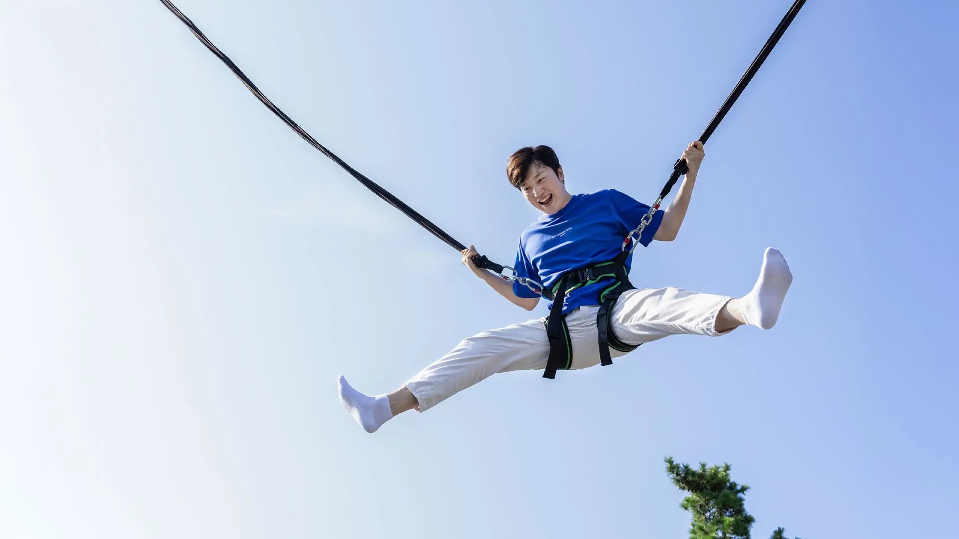 Eurobungy experience at Skyline Luge Tongyeong with guest jumping high in a safety harness under clear blue skies.